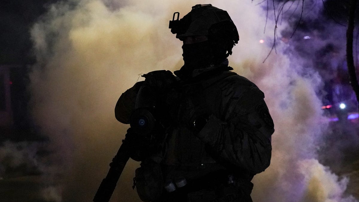 A federal agent walks near tear gas smoke after it was used on protesting community members, as tensions rise following the shooting death of an observer by an immigration officer, a week after a U.S. Immigration and Customs Enforcement (ICE) agent fatally shot Renee Nicole Good, in north Minneapolis, Minn. on Jan. 14, 2026.