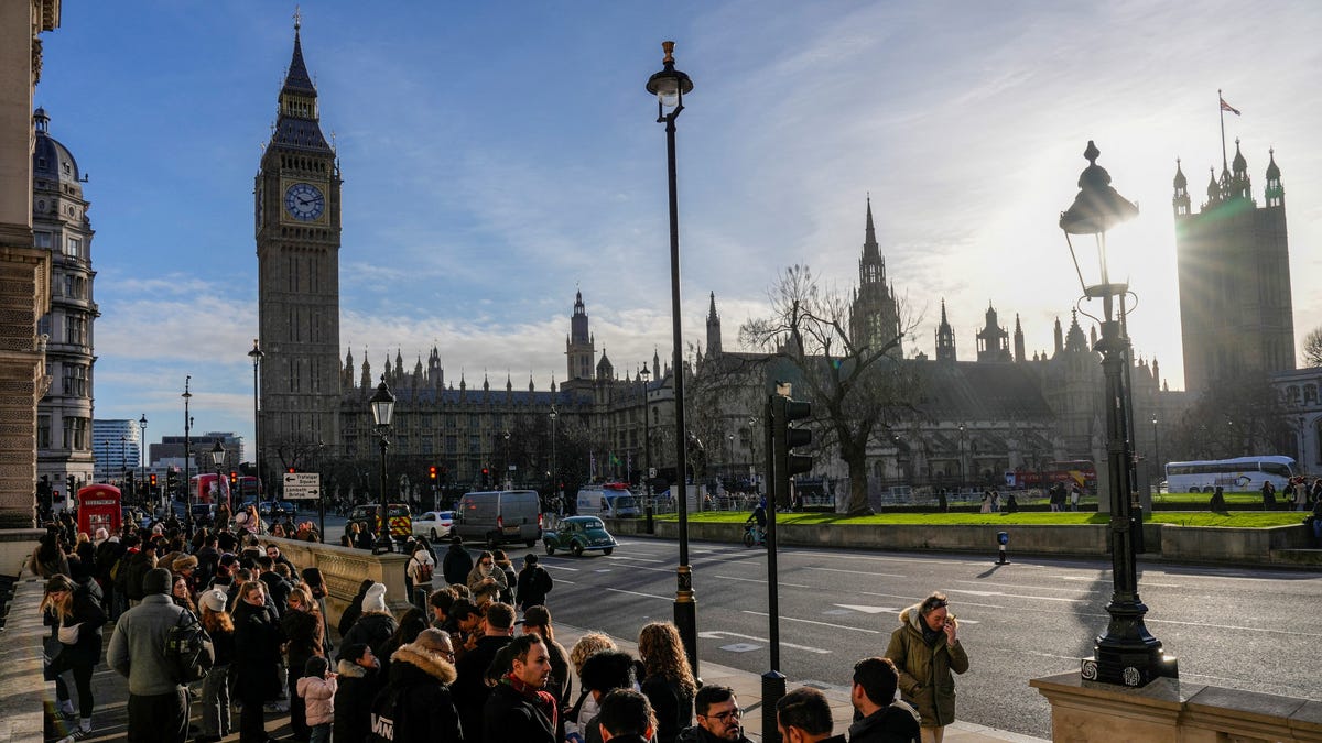 Tourists queue to take pictures next to a classic red phone box (L) during a visit to the Westminster area of central London on December, 30, 2025.