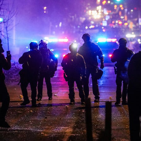 Federal agents stand guard after deploying tear gas as community members protest after federal law enforcement agents were involved in a shooting incident, a week after a U.S. Immigration and Customs Enforcement agent fatally shot Renee Nicole Good, in Minneapolis.