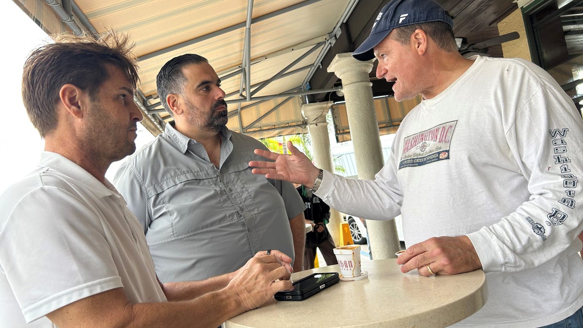 Nicolas Gutierrez, right, discusses the upcoming College Football Playoff National Championship game with friends Lawrence Valido, center, and Rafael Echarria, left, at La Carreta Restaurant on Bird Road in Miami, an epicenter of Miami's Cuban community.