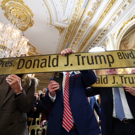 Attendees hold 'President Donald J. Trump Boulevard' street signs, at a ceremony held to dedicate a 4-mile stretch of road from West Palm Beach Airport to U.S. President Donald Trump's Mar-a-Lago estate as 'President Donald J. Trump Boulevard.'