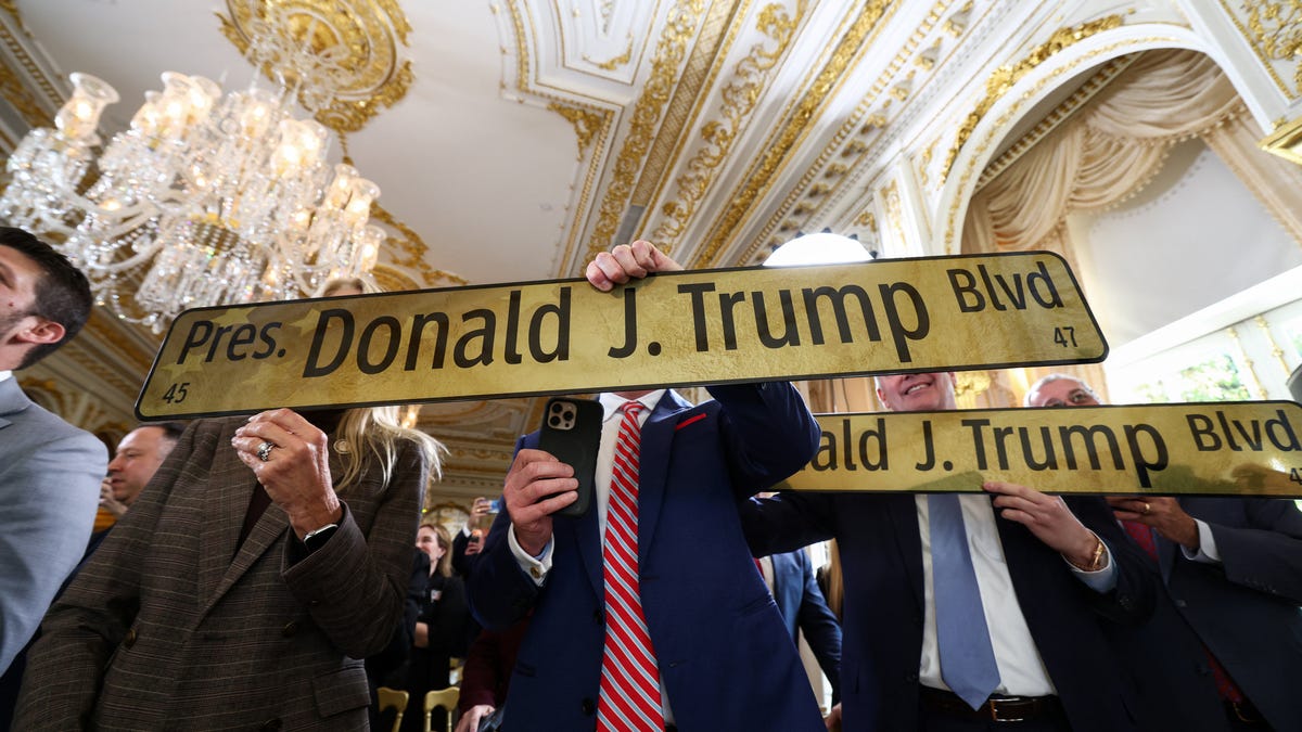 Attendees hold 'President Donald J. Trump Boulevard' street signs, at a ceremony held to dedicate a 4-mile stretch of road from West Palm Beach Airport to U.S. President Donald Trump's Mar-a-Lago estate as 'President Donald J. Trump Boulevard.'