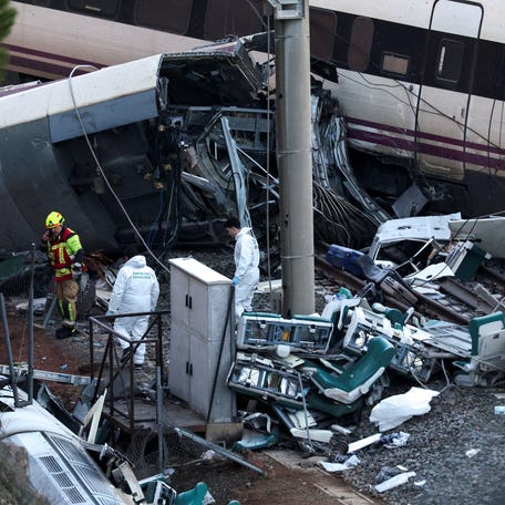 A firefighter and members of the Spanish Civil Guard work next to one of the trains involved in the accident.