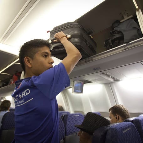 A passenger places his luggage into the overhead bin before an American Airlines flight from Miami to New York December 10, 2013.