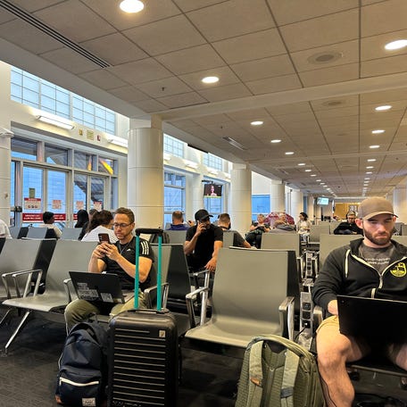 Travelers using their laptops before boarding a flight. A new survey shows nearly a quarter of U.S. workers are feeling burnt out.