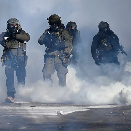 Federal agents point weapons amid tear gas fired at protesters on Jan. 24, 2026, in Minneapolis.