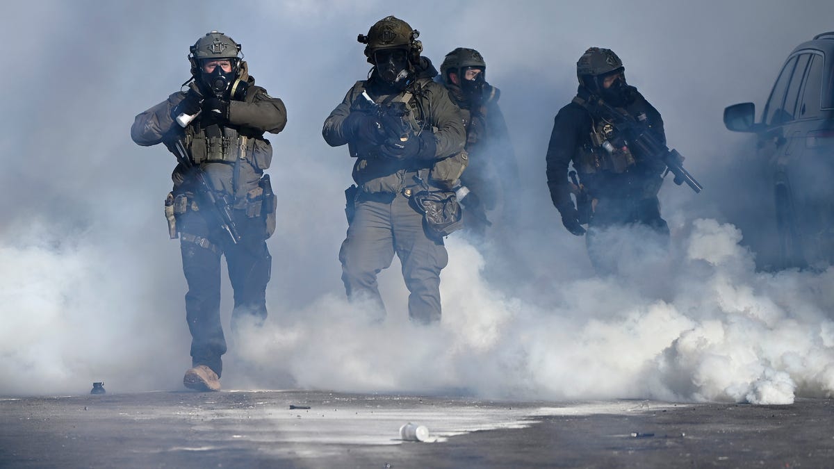 Federal agents point weapons amid tear gas fired at protestors. Earlier agents allegedly shot and killed a protestor amid a scuffle to arrest him on January 24, 2026 in Minneapolis.