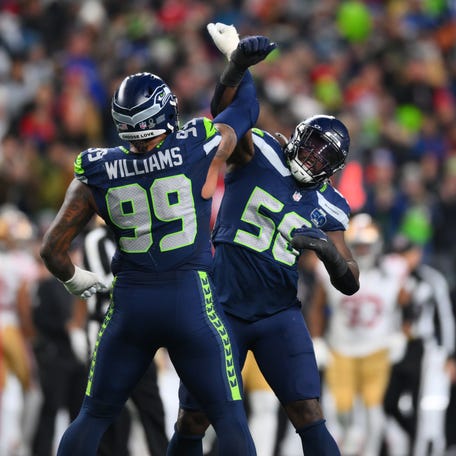 Seattle Seahawks defensive end Leonard Williams (99) and linebacker Derick Hall (58) react after the sack of San Francisco 49ers quarterback Brock Purdy (13) during the second half in an NFC Divisional Round game at Lumen Field.