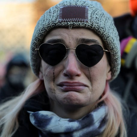A woman cries as people gather around a makeshift memorial at the site where a man identified as Alex Pretti was fatally shot by federal agents trying to detain him, in Minneapolis, Minnesota, U.S., January 24, 2026.