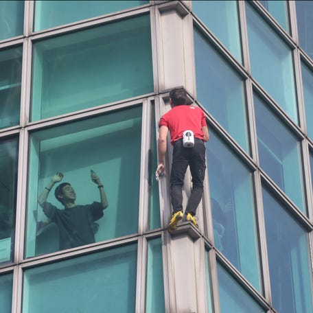 A building occupant uses his phone to record US rock climber Alex Honnold climbing the Taipei 101 building without ropes or safety gear in Taipei on Jan. 25, 2026.