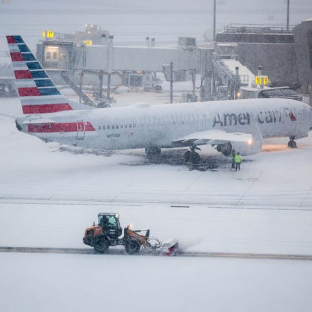 A snow removal machine is seen working while a Boeing 737 American Airlines passenger aircraft is parked at gate on the tarmac of LaGuardia airport in New York on Jan. 25, 2026. A massive winter storm on January 24, 2026 dumped snow and freezing rain on New Mexico and Texas as it swept across the United States towards the northeast, threatening tens of millions of Americans with blackouts, transportation chaos and bone-chilling cold. Shoppers stripped supermarket shelves as the National Weather Service   (NWS) forecast huge snowfall in some areas and possibly "catastrophic" ice accumulations.