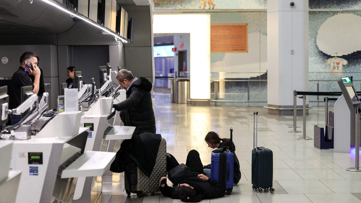 Passengers sit and lay on the ground as they speak to airlines employee following flight cancellations due to weather conditions at LaGuardia airport in New York on January 25, 2026. A massive winter storm on Jan. 24, 2026 dumped snow and freezing rain on New Mexico and Texas as it swept across the United States towards the northeast, threatening tens of millions of Americans with blackouts, transportation chaos and bone-chilling cold. Shoppers stripped supermarket shelves as the National Weather   Service (NWS) forecast huge snowfall in some areas and possibly "catastrophic" ice accumulations.