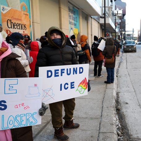 A demonstrator holds a sign to protest the presence of federal agents in Minneapolis prior to the start of an NBA game between the Golden State Warriors and Minnesota Timberwolves at Target Center on Jan. 25, 2026 in Minneapolis, Minn.