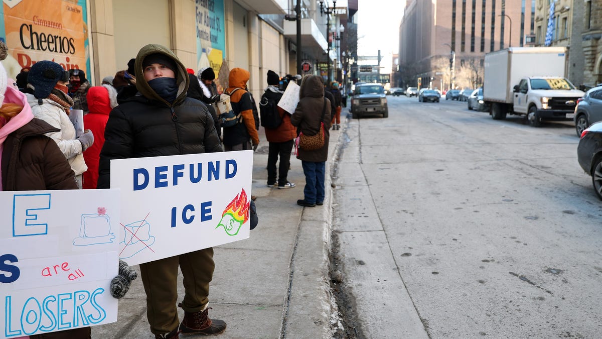 A demonstrator holds a sign to protest the presence of federal agents in Minneapolis prior to the start of an NBA game between the Golden State Warriors and Minnesota Timberwolves at Target Center on Jan. 25, 2026 in Minneapolis, Minn.