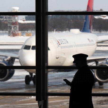 A pilot walks past a Delta Air Lines airplane as flights are delayed and cancelled following a significant winter storm at Ronald Reagan Washington National Airport in Arlington, Va., Jan. 26, 2026.