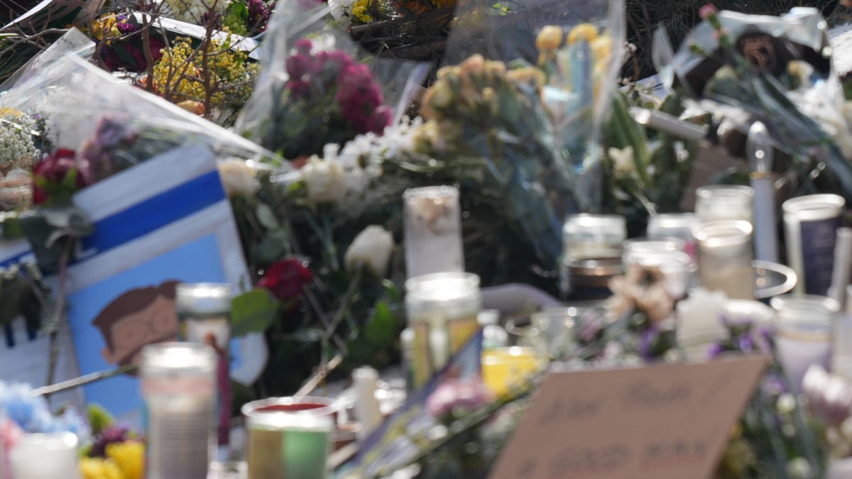 Mourners pay their respects at a memorial site on Nicolett Avenue in Minneapolis marking where Alex Pretti was shot and killed by federal immigration agents.