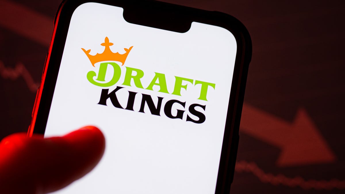 A DraftKings logo is displayed on a smartphone. DraftKings is a digital sports entertainment and gaming company, offering legal, regulated online sports betting