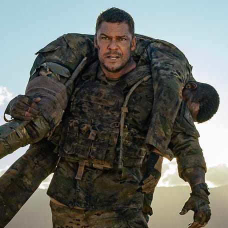 81 (Alan Ritchson, standing) carries the injured 7 (Stephan James) to safety in "War Machine."