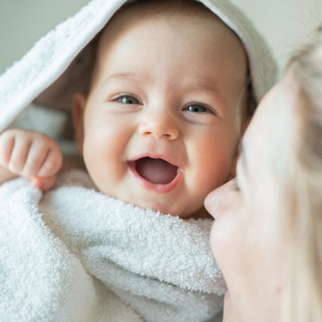 A mother carries her smiling baby girl.