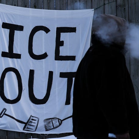A man walks past a sign hanging on a fence in Minneapolis, Minnesota, on February 3, 2026.
