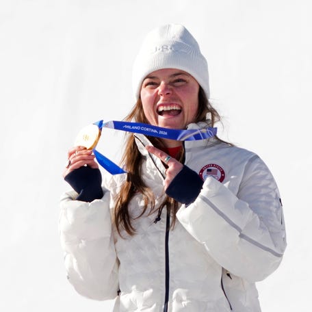 Feb 8, 2026; Cortina d'Ampezzo, Italy; Breezy Johnson of the United States celebrates with her gold medal, before it broke, after winning the women's downhill alpine skiing race during the Milano Cortina 2026 Olympic Winter Games at Tofane Alpine Skiing Centre.