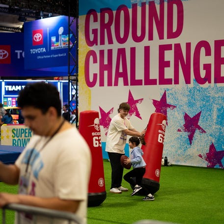 Nichols College junior Tucker Delaney helps a young fan through the NFL combine drill while working at the Super Bowl during this past weekend.