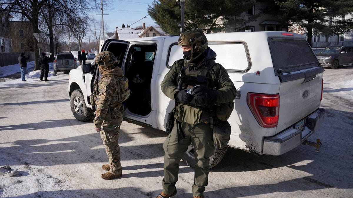 Federal immigration agents stand next to a vehicle as they conduct immigration enforcement tasks in south Minneapolis, Minnesota, U.S., Jan. 23, 2026.
