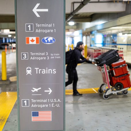A traveler pushes luggage past a sign for Canadian, international, and U.S. flights at Toronto Pearson International Airport on Aug. 11, 2025.