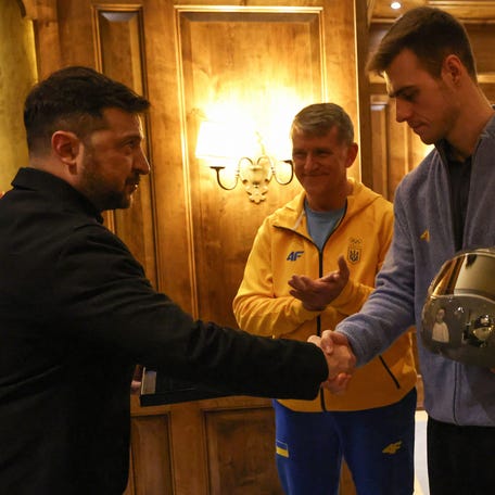 Ukrainian President Volodymyr Zelensky shakes hands with Ukrainian skeleton athlete Vladyslav Heraskevych a medal as they meet in Munich, southern Germany, on the sidelines of the 62nd Munich Security Conference (MSC) on February 13, 2026. Heraskevych was barred from the Milan-Cortina Games after refusing to back down from wearing a helmet adorned with pictures of Ukrainian sportsmen and women killed since Russian invaded in 2022. (Photo by Alexandra BEIER / AFP via Getty Images)