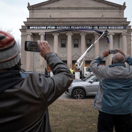 People take pictures as mourning bunting is hung on the front of the Rainbow PUSH Coalition's national headquarters to mourn the death of its founder Rev. Jesse Jackson on February 17, 2026 in Chicago, Illinois.