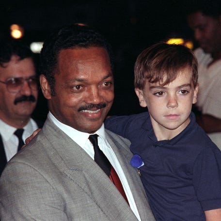 Senator Jesse Jackson carries Stuart Lockwood, a five-year-old British hostage who appeared on Iraqi T.V. with Saddam Hussein, on their arrival at London's Heathrow Airport on September 2, 1990.