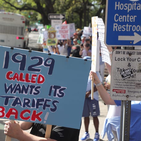 A protester holds a sign criticizing tariffs during a march against President Donald Trump's policies on April 5, 2025, in Savannah, Georgia.