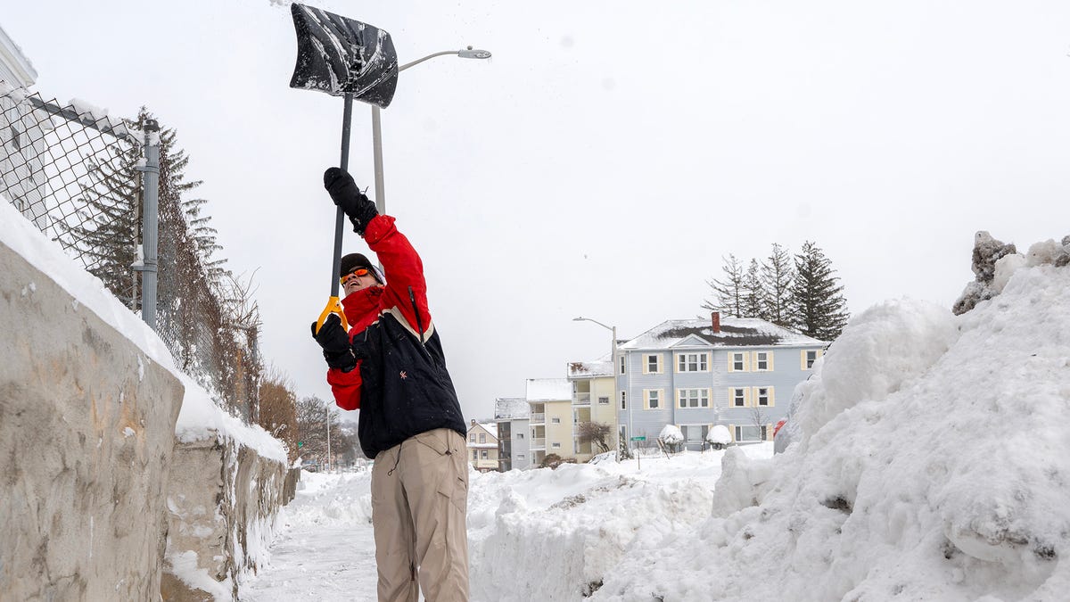 Zach Chapin tosses shovels of snow over his shoulder onto his elevated yard above while clearing the sidewalk in front of his Main Street home Feb. 23.