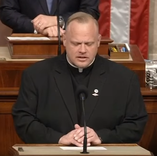 The Rev. Jonathan Slavinskas delivers a prayer before the U.S. House of Representatives on Monday, Feb. 23. Behind him is House Speaker Mike Johnson.
