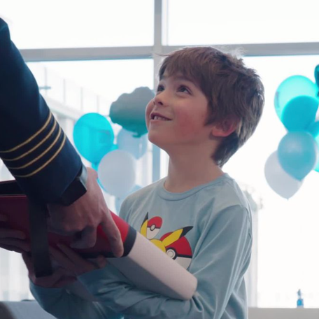 Seven-year-old Reid smiles while being handed a binder of Pokémon cards.