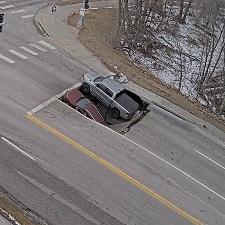 A traffic camera captured two vehicles falling into an Omaha sinkhole as bystanders rushed in to rescue trapped drivers before authorities arrived.