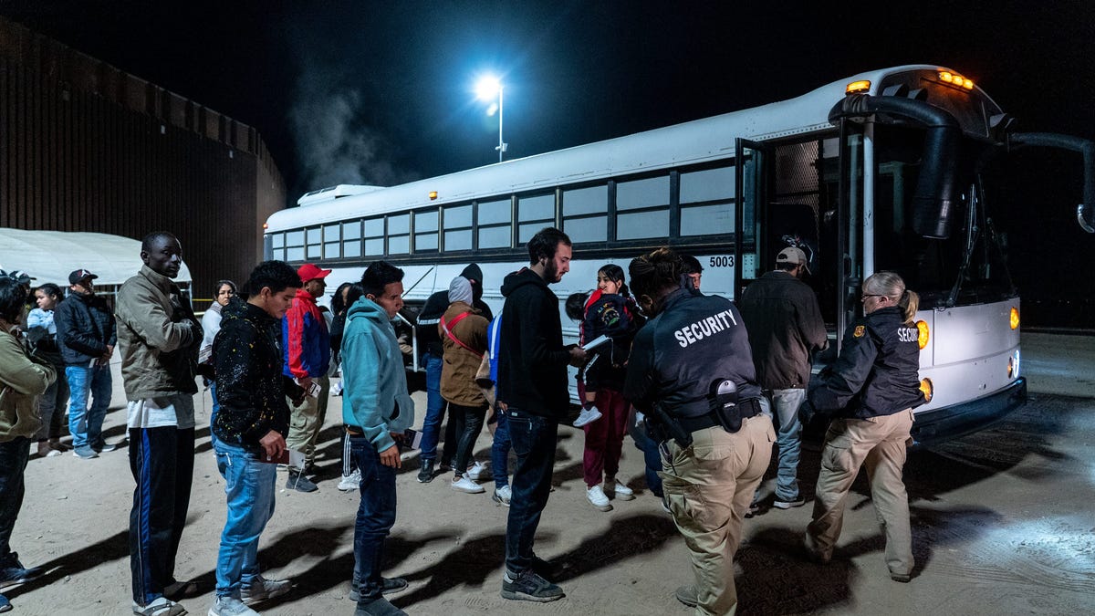 Migrants and asylum seekers are patted down by security personnel as they prepare to board a bus after being detained by U.S. Border Patrol agents after crossing the U.S.-Mexico border in Somerton, Arizona, on May 11, 2023.