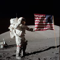 Astronaut Eugene A. Cernan, Apollo 17 commander, is photographed next to the deployed United States flag during lunar surface extravehicular activity (EVA) at the Taurus-Littrow landing site. The highest part of the flag appears to point toward our planet Earth in the distant background. This picture was taken by scientist-astronaut Harrison H. Schmitt, lunar module pilot.