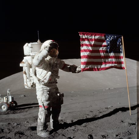 Astronaut Eugene A. Cernan, Apollo 17 commander, is photographed next to the deployed United States flag during lunar surface extravehicular activity (EVA) at the Taurus-Littrow landing site. The highest part of the flag appears to point toward our planet Earth in the distant background. This picture was taken by scientist-astronaut Harrison H. Schmitt, lunar module pilot.
