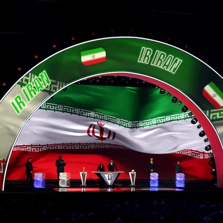 WASHINGTON, DC - DECEMBER 05: Draw assistant Tom Brady, Draw assistant Shaquille O'Neal, Co-Conductor Samantha Johnson, FIFA Legend Rio Ferdinand, Draw assistant Aaron Judge and Draw assistant Wayne Gretzky stand on stage as Iran is illuminated on the screen during the FIFA World Cup 2026 Official Draw at John F. Kennedy Center for the Performing Arts on December 05, 2025 in Washington, DC.