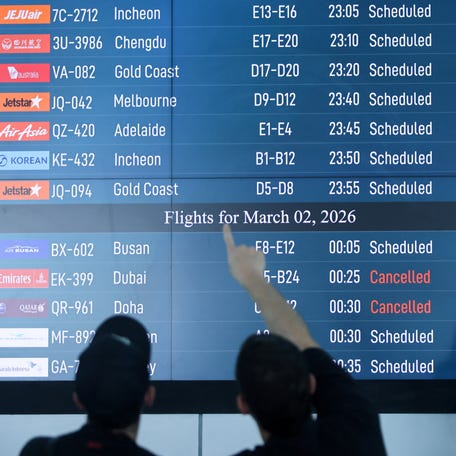 Passengers look at departure board at I Gusti Ngurah Rai International Airport as some flights to Dubai and Doha cancelled following strikes on Iran launched by the United States and Israel.