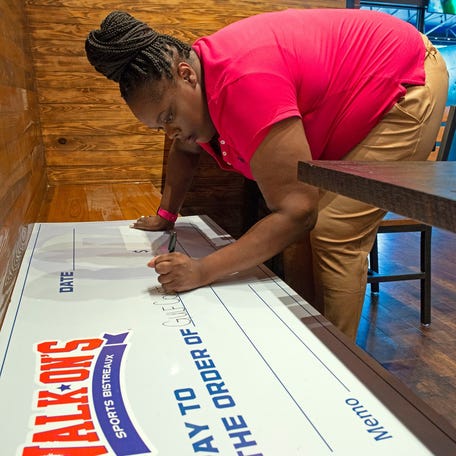 Walk-On's employee Latasha Goodwyn writes the new restaurant's first charitable donation to the community, a $5,000 check to the Gulf Coast Kids House on Monday, Aug. 29, 2022.    Walk On S