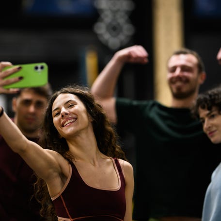 Four friends gather together in a gym to take a selfie after their workout. They smile and show off their muscles, enjoying the moment and celebrating their fitness journey.