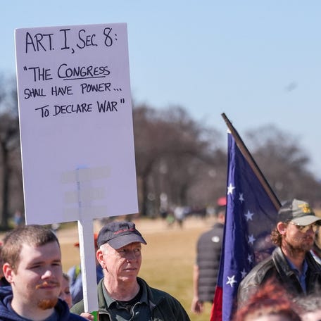 A demonstrator holds a sign referencing Article I, Section 8 of the U.S. Constitution and Congress' power to declare war, following strikes by Israel and the U.S. on Iran, during the March4Democracy rally and march in Washington D.C., U.S., February 28, 2026. REUTERS/Leah Millis