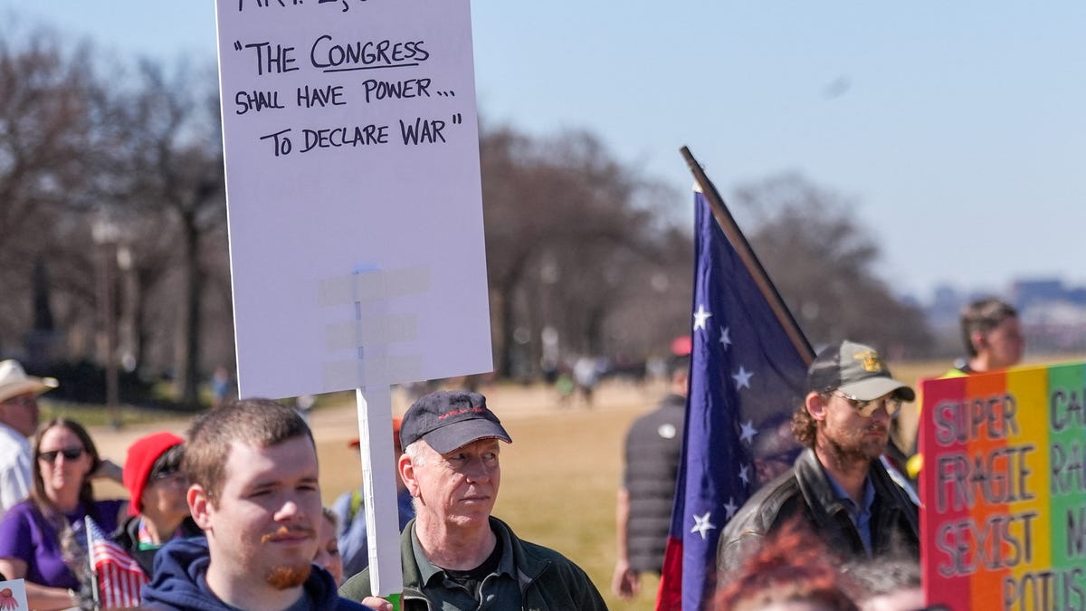 A demonstrator holds a sign referencing Article I, Section 8 of the U.S. Constitution and Congress' power to declare war, following strikes by Israel and the U.S. on Iran, during the March4Democracy rally and march in Washington D.C., U.S., February 28, 2026. REUTERS/Leah Millis