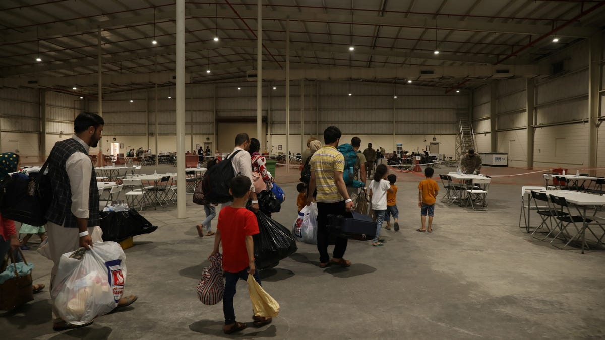 Special Immigrants from Afghanistan walk through the in-processing building after their evacuation at Camp As Sayliyah, Qatar, August 20, 2021. Picture taken August 20, 2021. U.S. Army/Sgt. Jimmie Baker/Handout via REUTERS THIS IMAGE HAS BEEN SUPPLIED BY A THIRD PARTY.