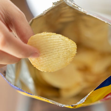 Hand hold potato chips with snack bag