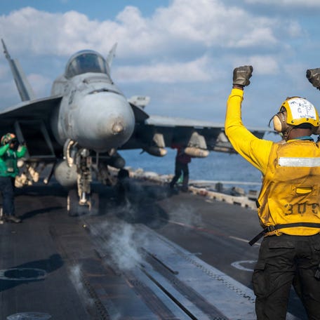 A U.S. Navy sailor signals an F/A-18E Super Hornet on the flight deck of the aircraft carrier USS Abraham Lincoln at an undisclosed location March 4, 2026.
