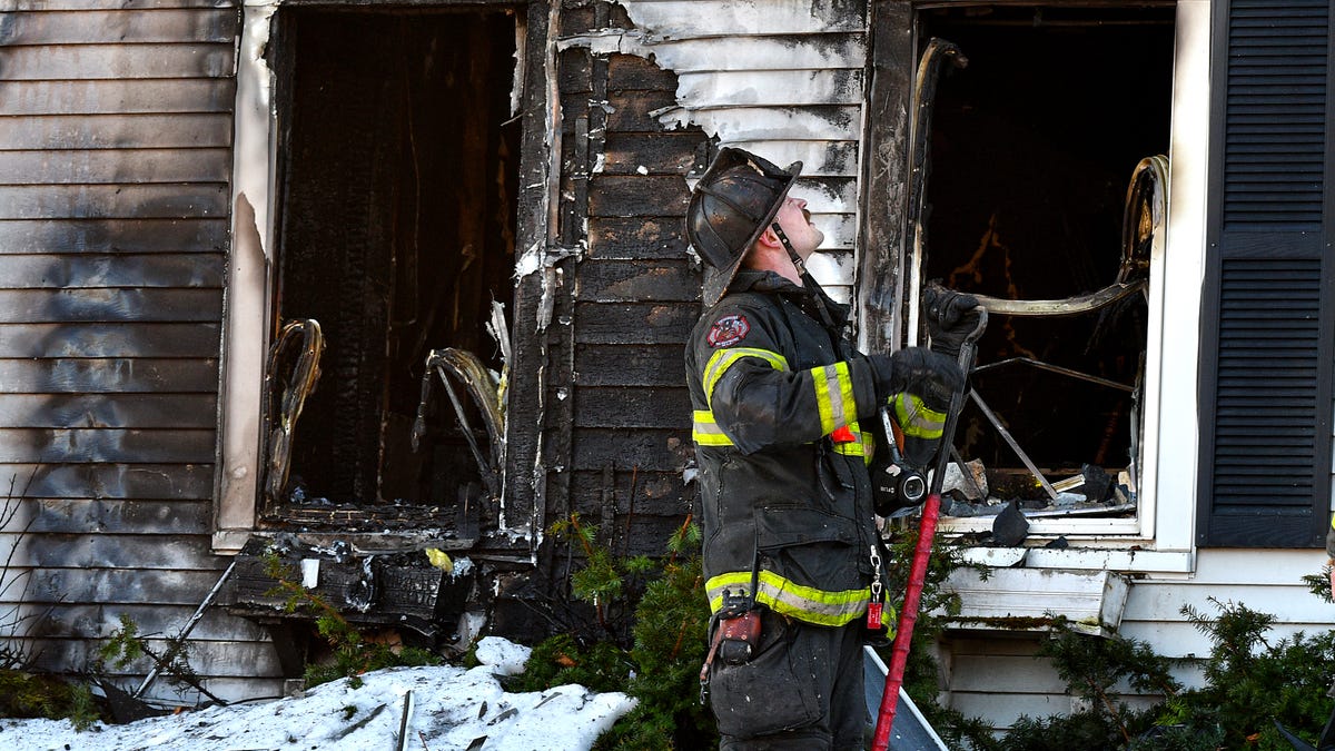 A Southbridge firefighter moves to the front of the house while helping to fight a fire at 417 South St. in Southbridge on March 9.