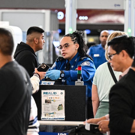 A Transportation Security Administration agent works at a security checkpoint as travelers wait in line at George Bush Intercontinental Airport in Houston, Texas, on Nov. 7, 2025.